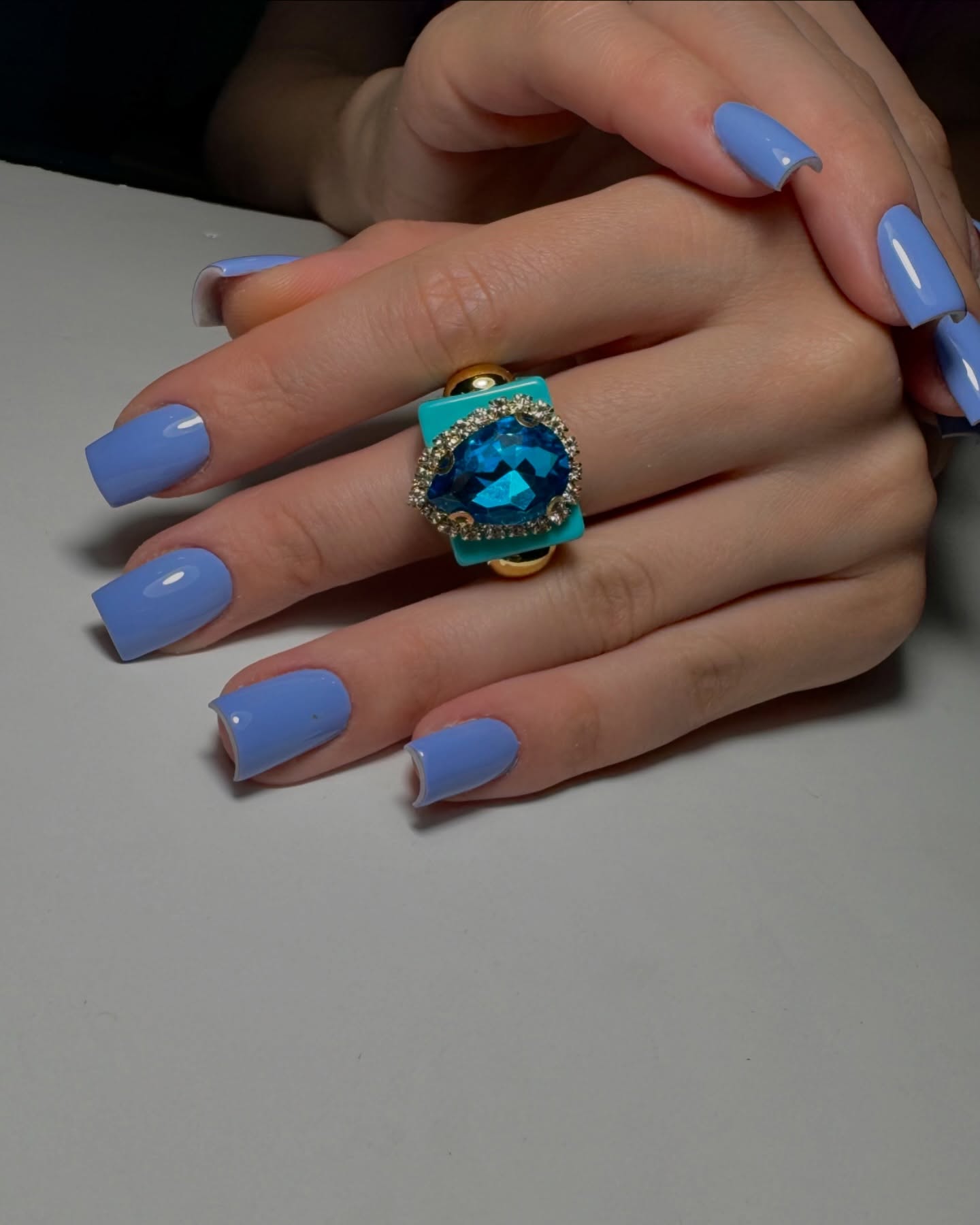 Periwinkle blue square nails styled with a turquoise statement ring